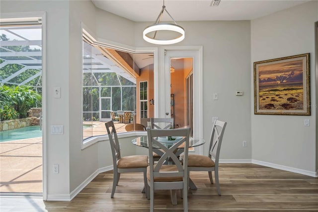 dining area featuring wood finished floors, a sunroom, and baseboards
