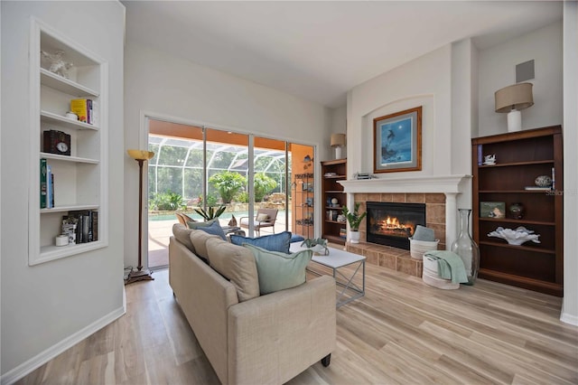 living area featuring wood finished floors, built in shelves, a fireplace, and baseboards