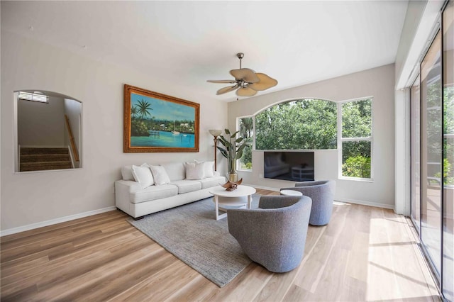living room with light wood-style floors, arched walkways, and plenty of natural light