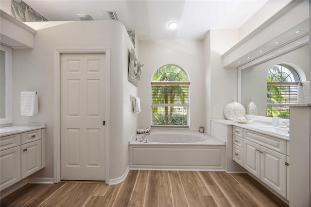 full bath with vanity, wood finished floors, plenty of natural light, and a garden tub