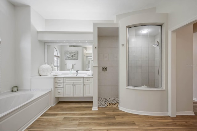 bathroom with walk in shower, vanity, wood finished floors, and a bath
