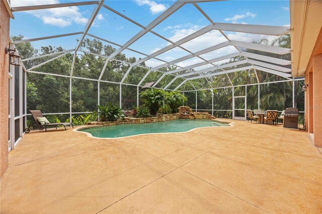 outdoor pool with a patio area, grilling area, and glass enclosure