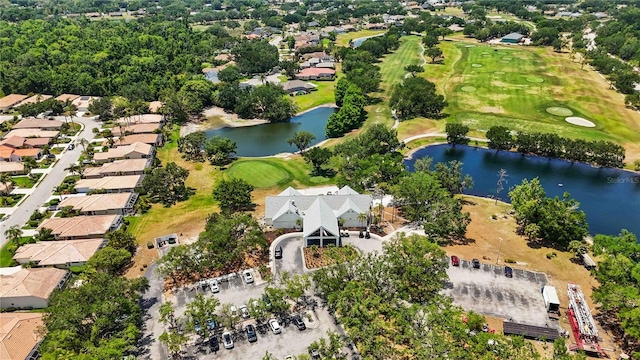 view of property location with a golf course, a nearby body of water, and nearby suburban area