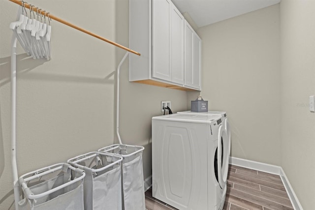 laundry area with washing machine and clothes dryer, dark wood-style flooring, baseboards, and cabinet space