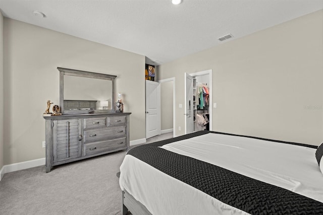 carpeted bedroom with baseboards, visible vents, and a spacious closet