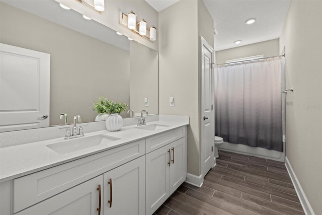 full bath featuring a sink, baseboards, toilet, and wood finished floors