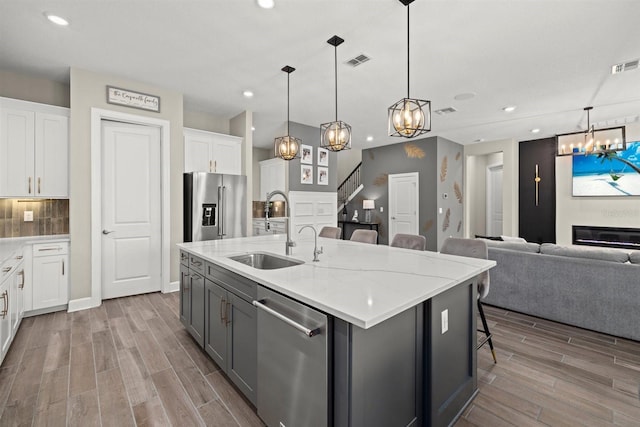 kitchen featuring appliances with stainless steel finishes, a sink, a chandelier, wood finished floors, and visible vents