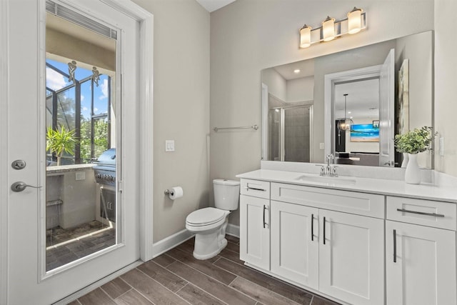 full bathroom featuring a stall shower, wood finished floors, vanity, baseboards, and toilet