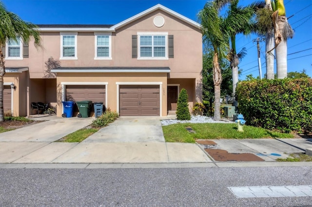 view of property featuring concrete driveway, a garage, and stucco siding