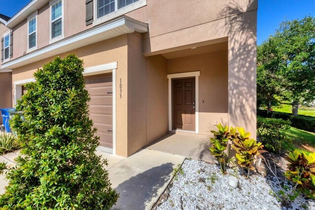 property entrance featuring an attached garage and stucco siding