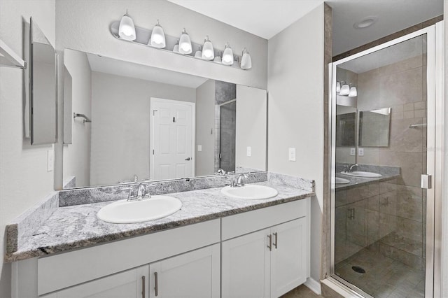 bathroom with a sink, a stall shower, and double vanity