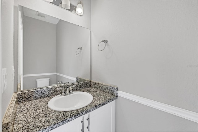 bathroom with toilet, visible vents, and vanity