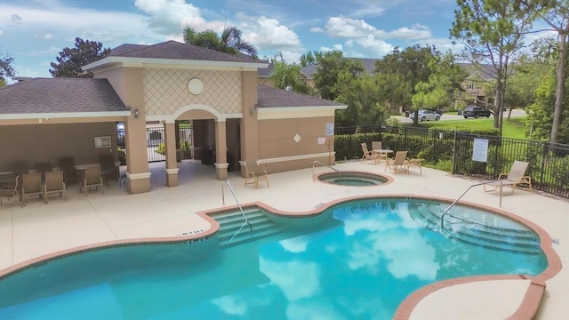 community pool featuring fence, a patio, and a hot tub