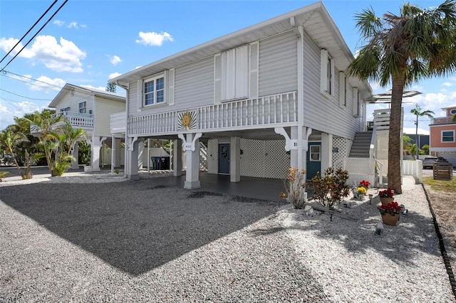 back of property featuring a carport, gravel driveway, and stairway