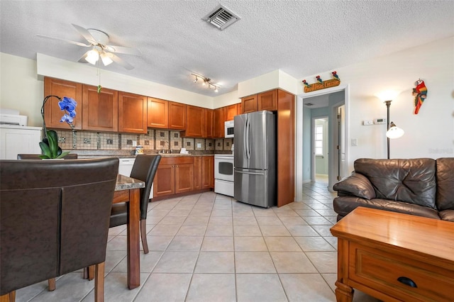 kitchen with white appliances, a ceiling fan, open floor plan, backsplash, and visible vents