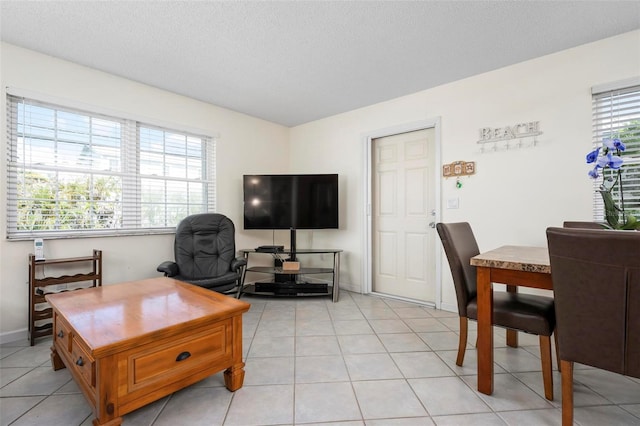 living room with light tile patterned floors, a textured ceiling, and baseboards