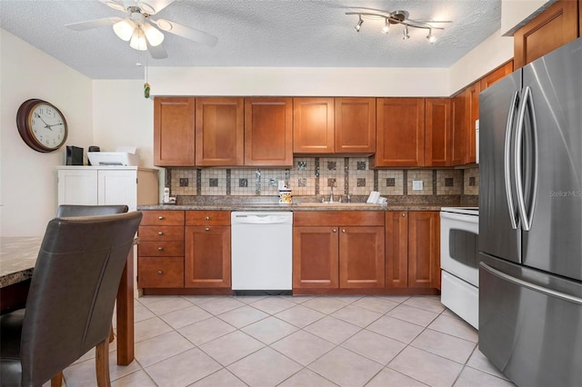 kitchen with a sink, brown cabinets, tasteful backsplash, and white appliances