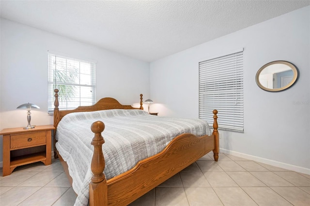 bedroom with baseboards, a textured ceiling, and light tile patterned flooring