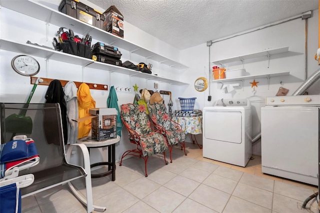 clothes washing area with laundry area, washer and clothes dryer, a textured ceiling, and tile patterned flooring