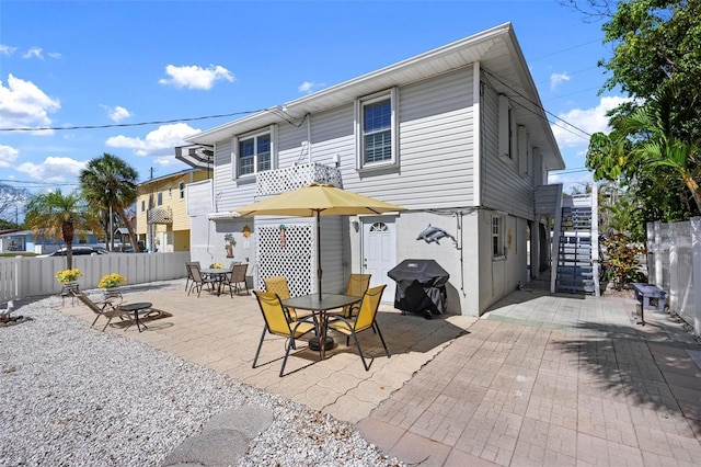 rear view of house featuring stairway, a patio, fence, and outdoor dining area