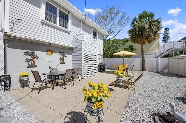 view of patio featuring fence, a storage unit, an outbuilding, and outdoor dining area