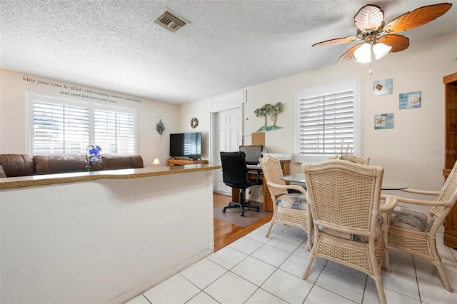 dining space with visible vents, a textured ceiling, ceiling fan, and light tile patterned flooring