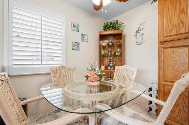 dining area featuring baseboards, ceiling fan, and a textured ceiling