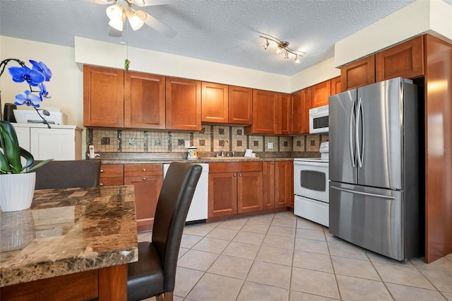 kitchen with brown cabinetry, ceiling fan, backsplash, and white appliances