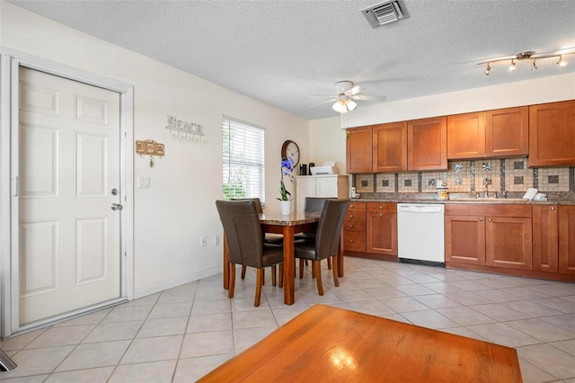 kitchen with visible vents, white dishwasher, brown cabinets, a sink, and backsplash