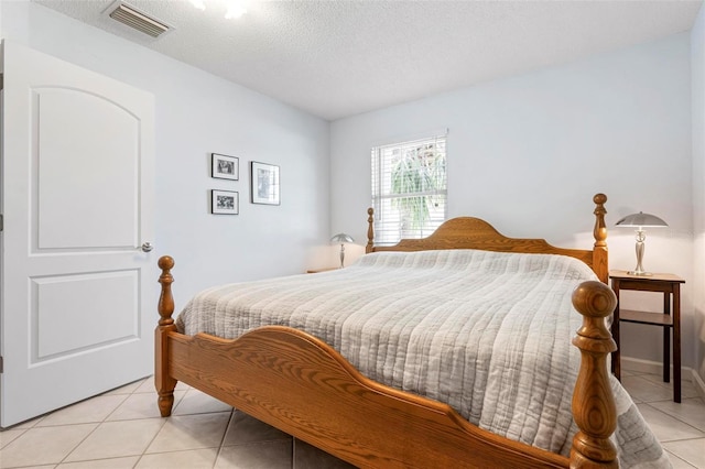 bedroom with light tile patterned floors, a textured ceiling, and visible vents