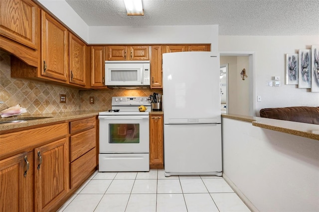 kitchen with light tile patterned flooring, white appliances, a textured ceiling, brown cabinetry, and tasteful backsplash