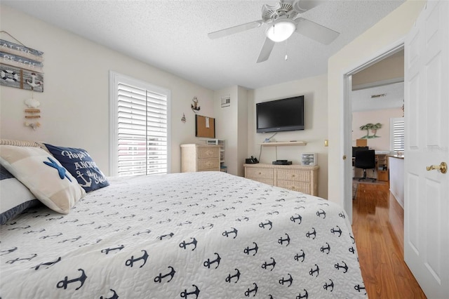 bedroom featuring a textured ceiling, a ceiling fan, and wood finished floors