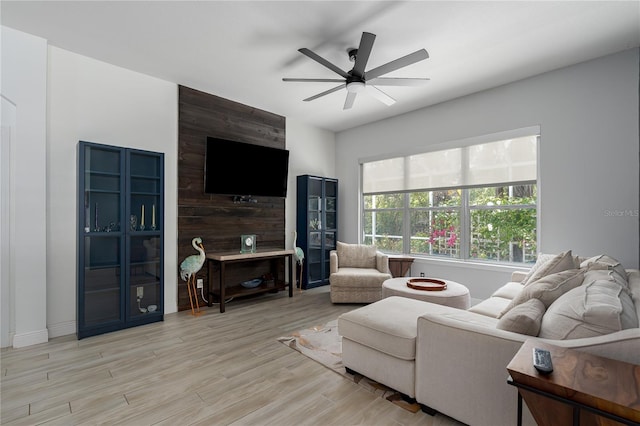 living room with ceiling fan, baseboards, and wood finished floors
