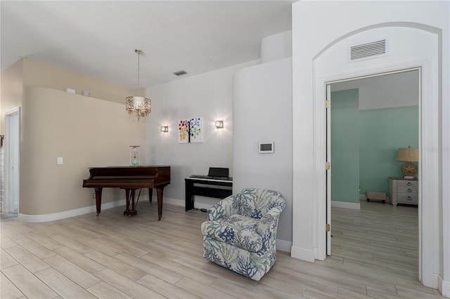living area featuring an inviting chandelier, visible vents, and light wood-style floors
