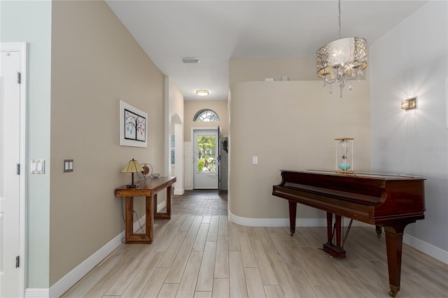 entryway featuring an inviting chandelier, baseboards, visible vents, and light wood-style floors