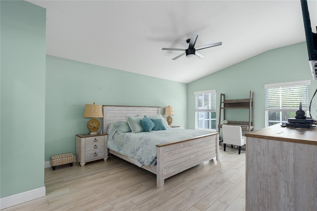 bedroom with lofted ceiling, multiple windows, baseboards, and light wood-style flooring