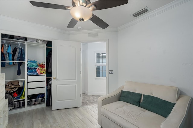 sitting room with ornamental molding, a ceiling fan, visible vents, and wood finished floors
