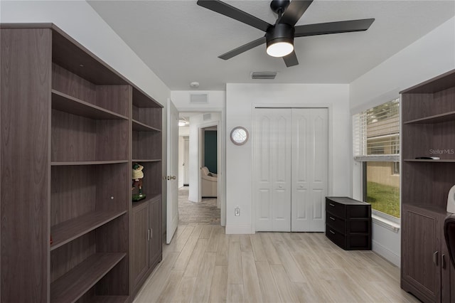 unfurnished office with light wood-type flooring, baseboards, visible vents, and ceiling fan