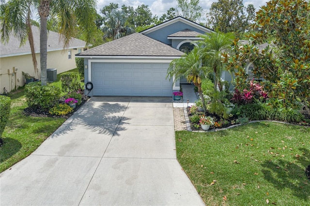 view of front of home with cooling unit, an attached garage, a shingled roof, concrete driveway, and a front yard