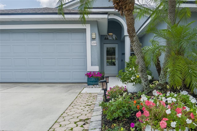 property entrance featuring driveway, stucco siding, and an attached garage