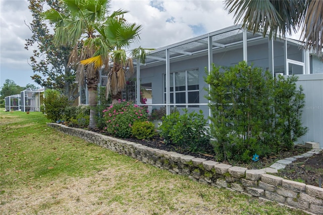 view of side of property with a lawn and glass enclosure