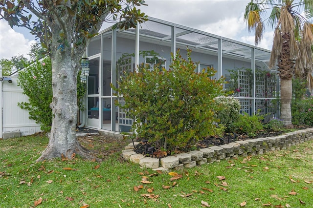 view of side of property featuring a yard and glass enclosure