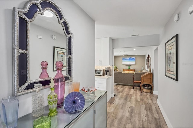 interior space featuring visible vents, baseboards, light wood-style floors, and a toaster