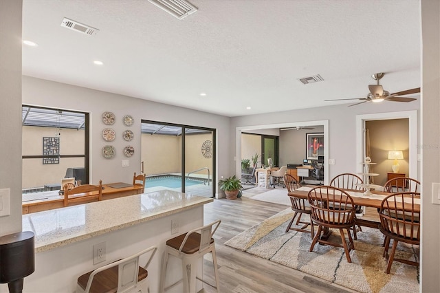 dining space featuring light wood-style floors, a ceiling fan, and visible vents