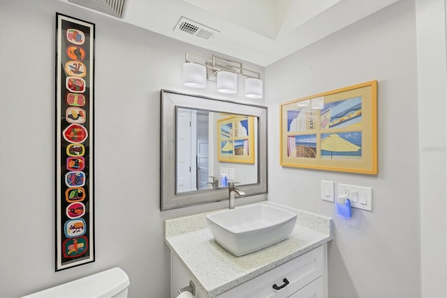 half bath featuring vanity, toilet, and visible vents