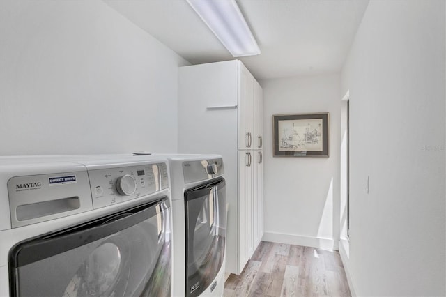 laundry room with cabinet space, baseboards, light wood-type flooring, and washer and dryer