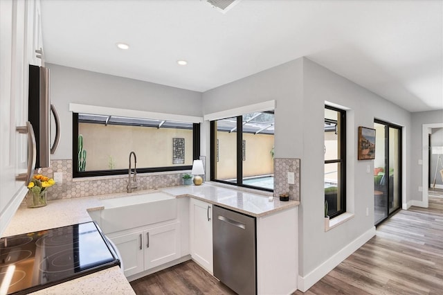 3955 Glen Oaks Manor Dr, Sarasota, FL 34232 - kitchen featuring dishwasher, white cabinets, wood finished floors, tasteful backsplash, and light stone countertops