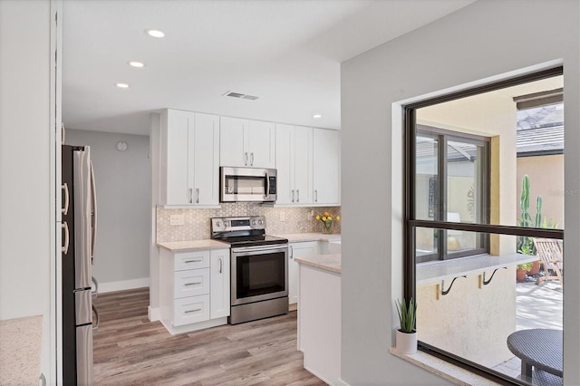 3955 Glen Oaks Manor Dr, Sarasota, FL 34232 - kitchen featuring appliances with stainless steel finishes, tasteful backsplash, white cabinets, light wood-style floors, and recessed lighting