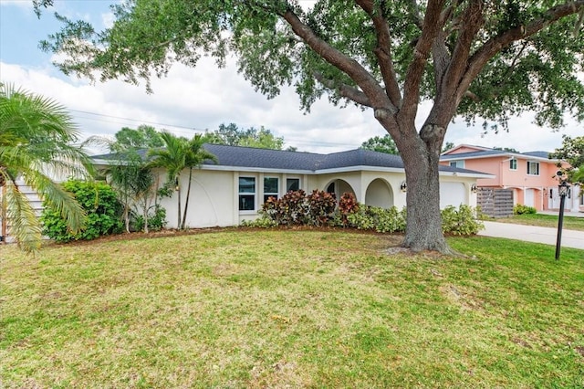 ranch-style home featuring a front yard, stucco siding, driveway, and a garage