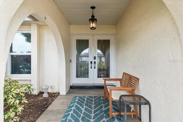 entrance to property with stucco siding, visible vents, and french doors